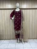 Maroon traditional outfit with intricate patterns on a mannequin against a striped