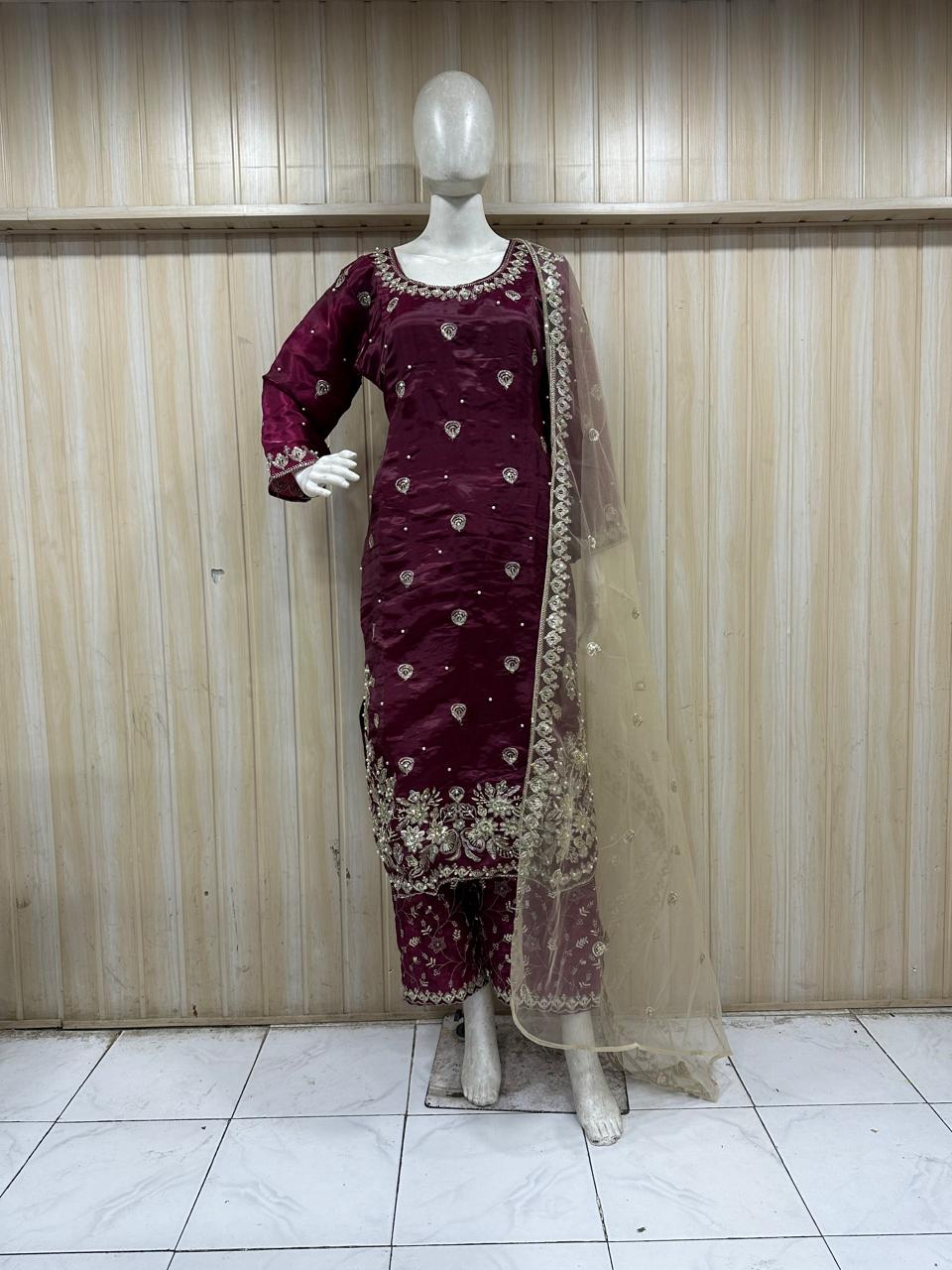 Maroon traditional outfit with intricate patterns on a mannequin against a striped