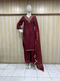 Maroon traditional outfit with intricate patterns on a mannequin against a striped