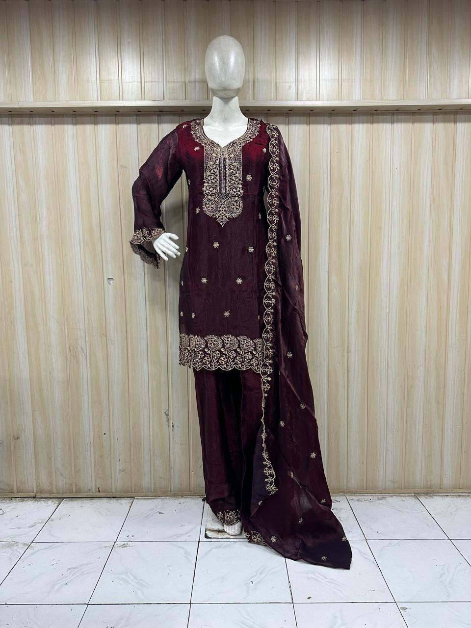 Maroon embroidered traditional outfit on a mannequin against a striped