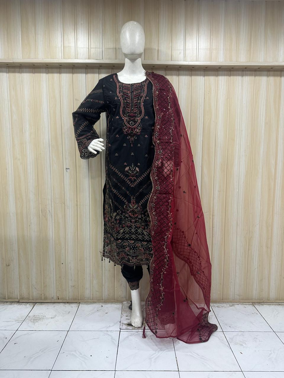 Mannequin wearing a black embroidered dress with a red dupatta against a striped
