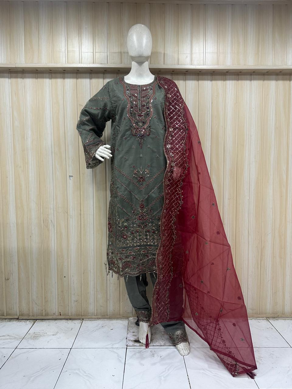 Mannequin wearing a green embroidered kurta with a red dupatta against a striped