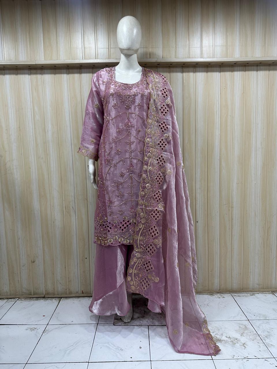 Mannequin wearing a pink embroidered outfit with a sheer dupatta against a striped