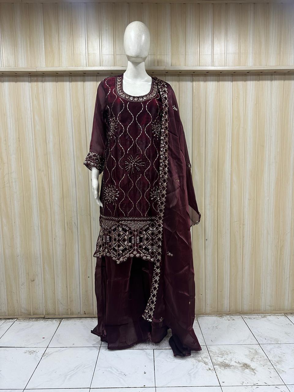 Mannequin wearing a maroon embroidered outfit with a sheer dupatta against a striped