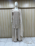 Mannequin wearing a beige outfit with a lace top and long skirt against a striped