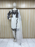 White dress with black embroidery on a mannequin against a wooden panel background