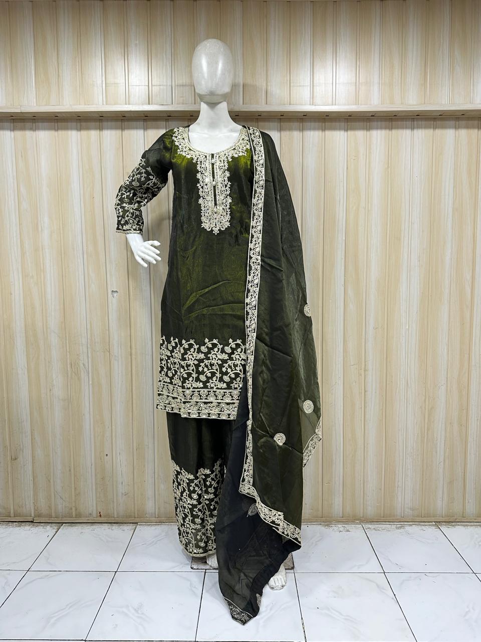 Green and black traditional outfit with white embroidery on a mannequin against a striped