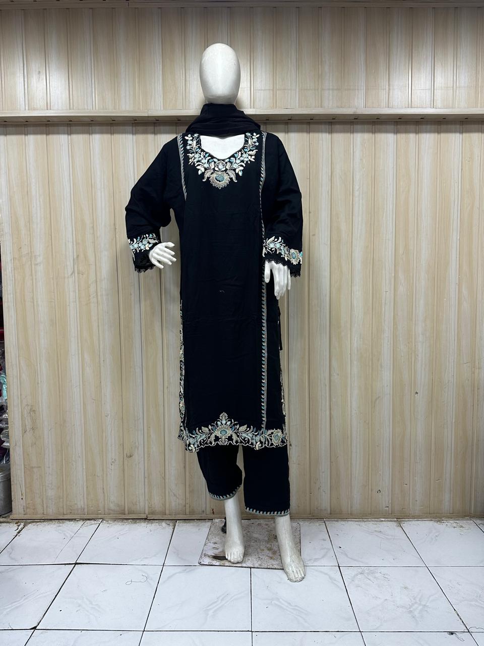 Black traditional outfit with white embroidery on a mannequin against a striped