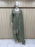 green traditional outfit with white embroidery on a mannequin against a striped