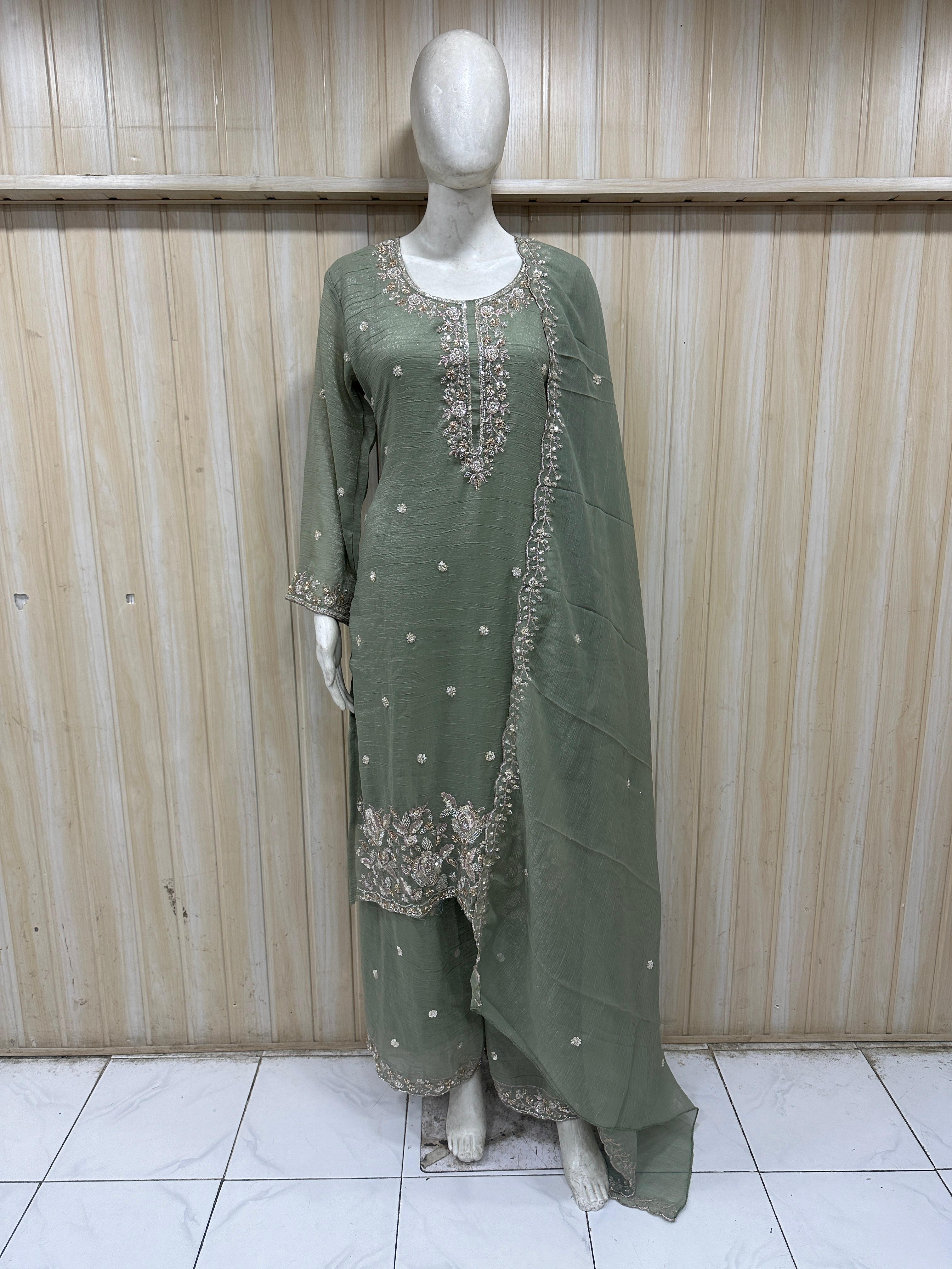 green traditional outfit with white embroidery on a mannequin against a striped