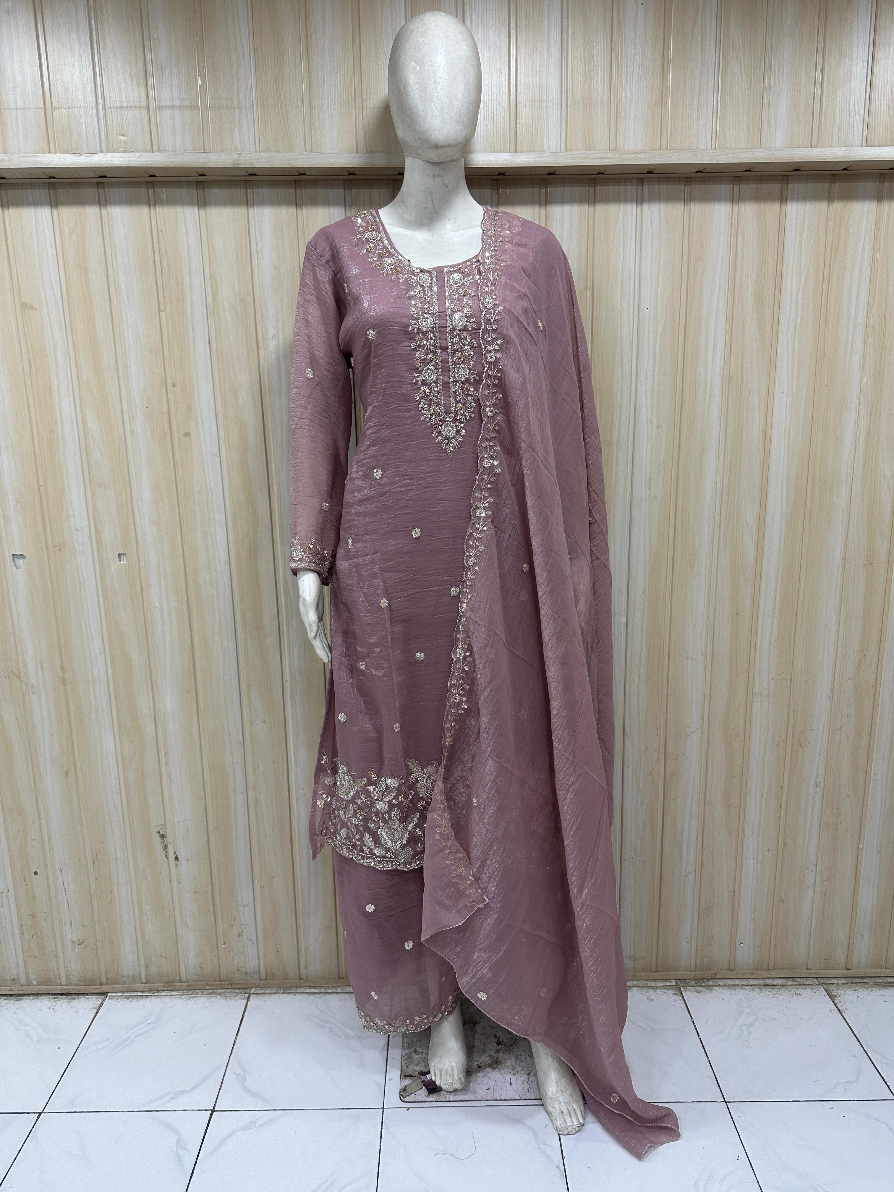 Mannequin wearing a mauve embroidered traditional outfit against a wooden panel background