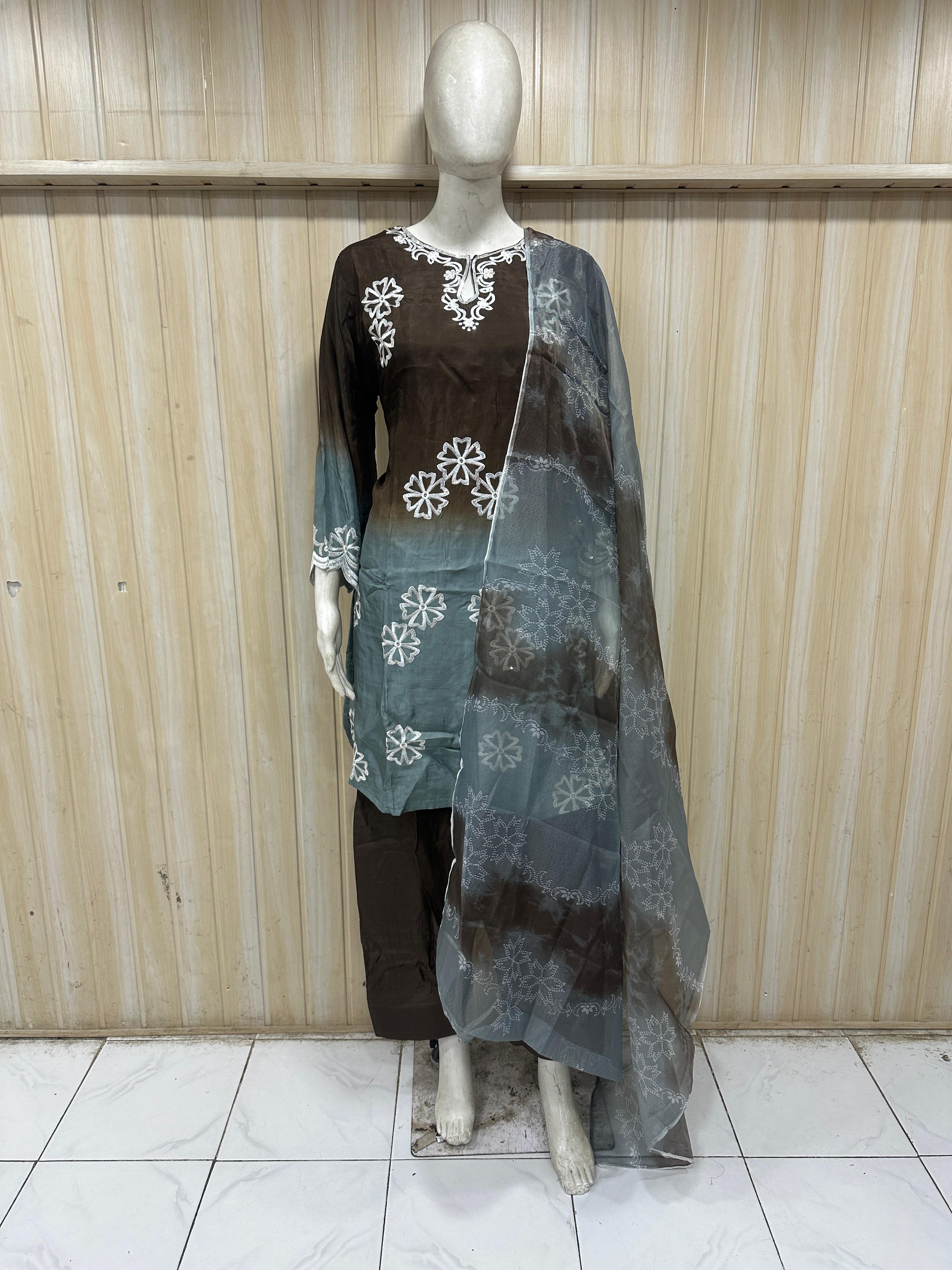 grey brown embroidered outfit on a mannequin against a striped