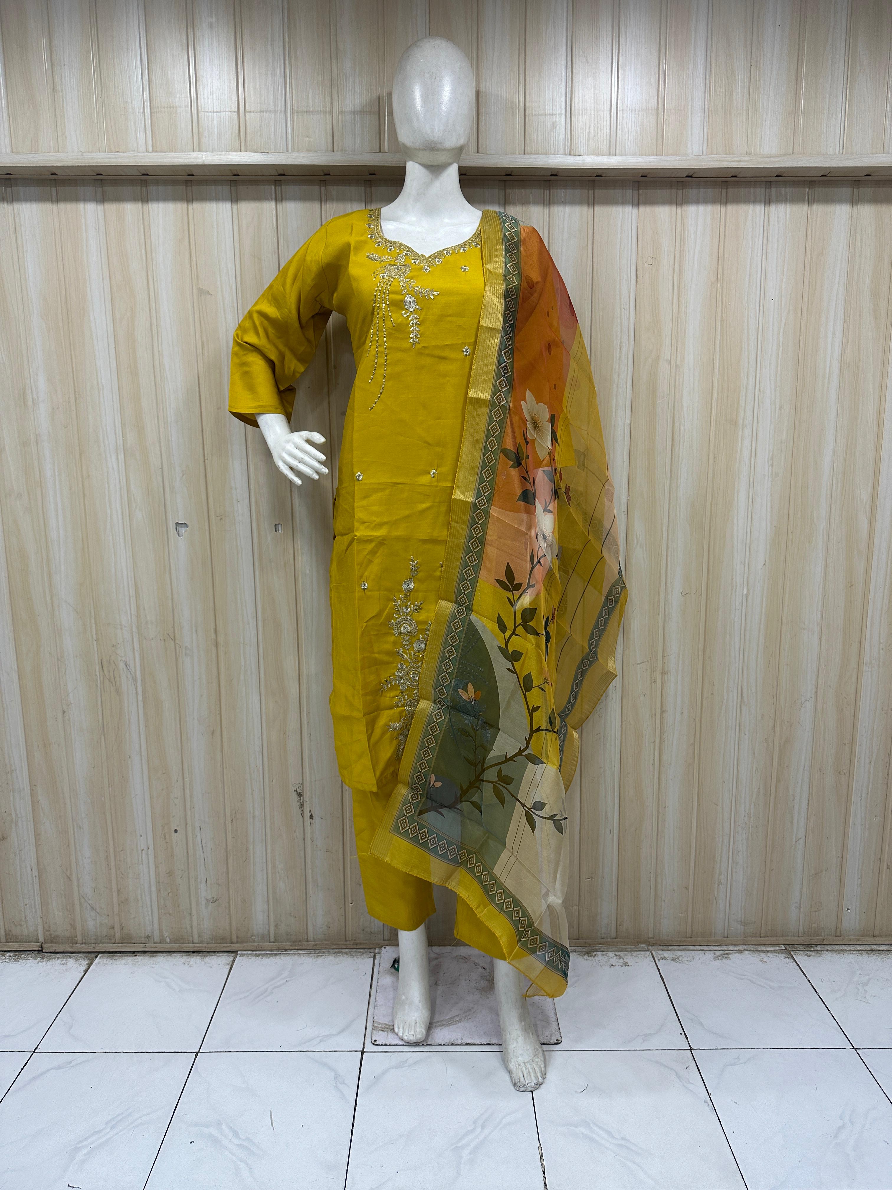 Mannequin wearing a green embroidered outfit with a matching dupatta against a striped