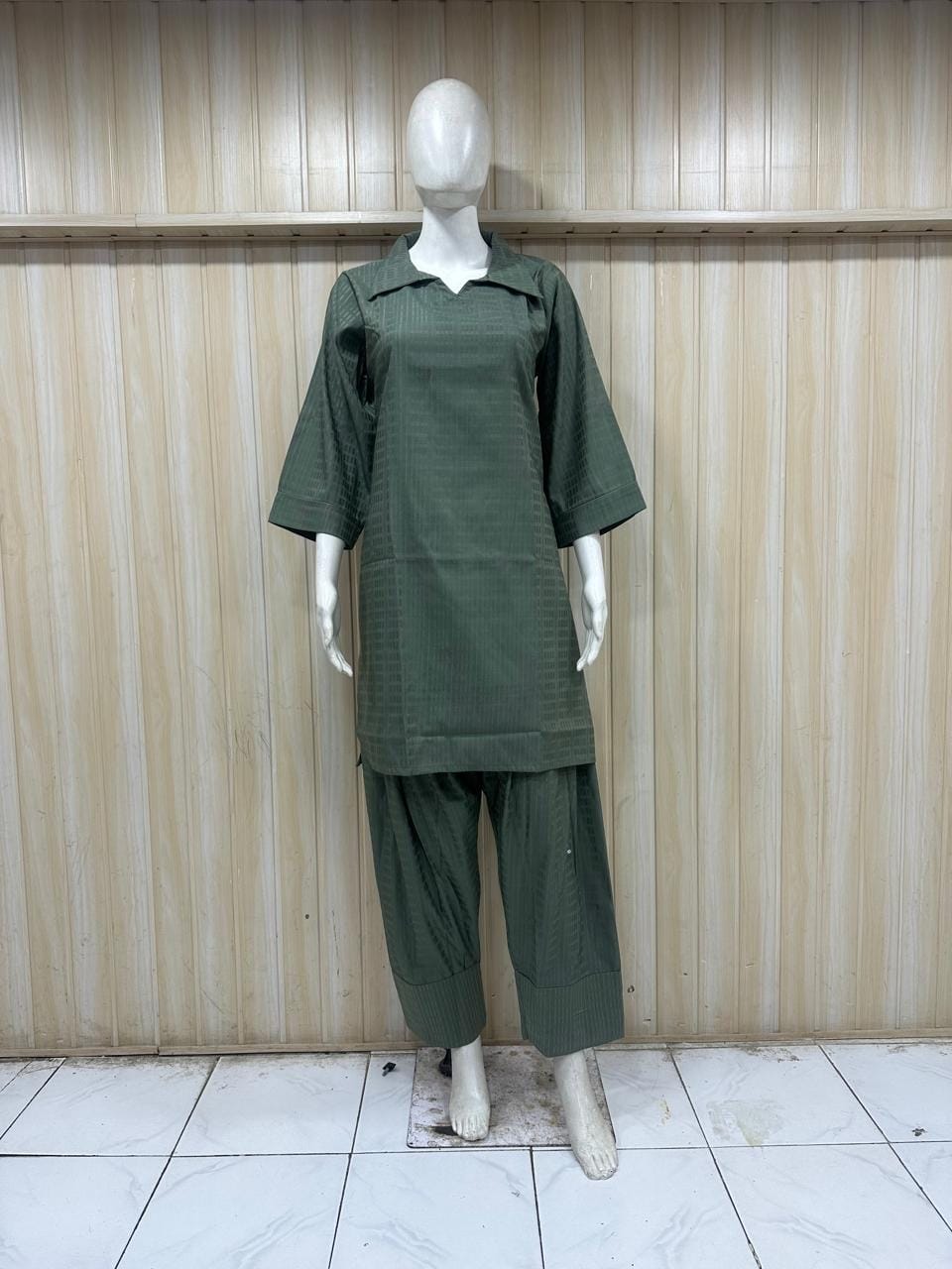 Mannequin wearing a grey embroidered outfit with a matching dupatta against a striped