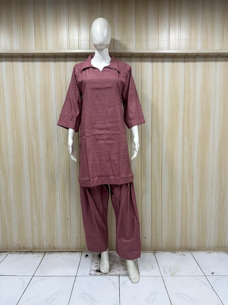 Mannequin wearing a maroon outfit against a striped