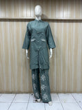 Green raincoat and pants on a mannequin against a wooden panel background