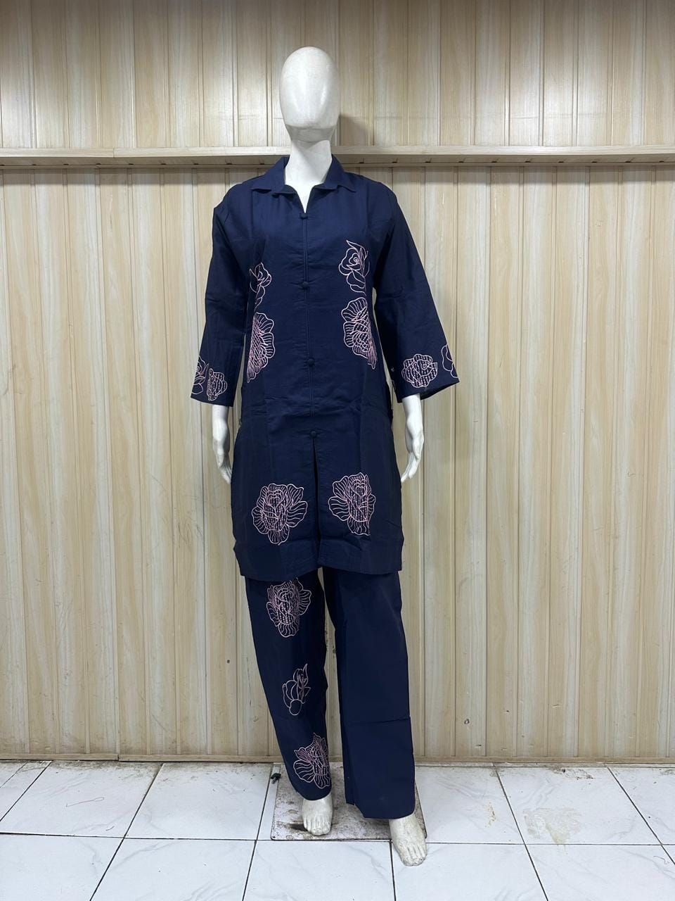 Navy blue outfit with patterns on a mannequin against a striped