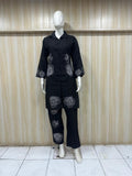 Black outfit with white floral patterns on a mannequin against a wooden panel background