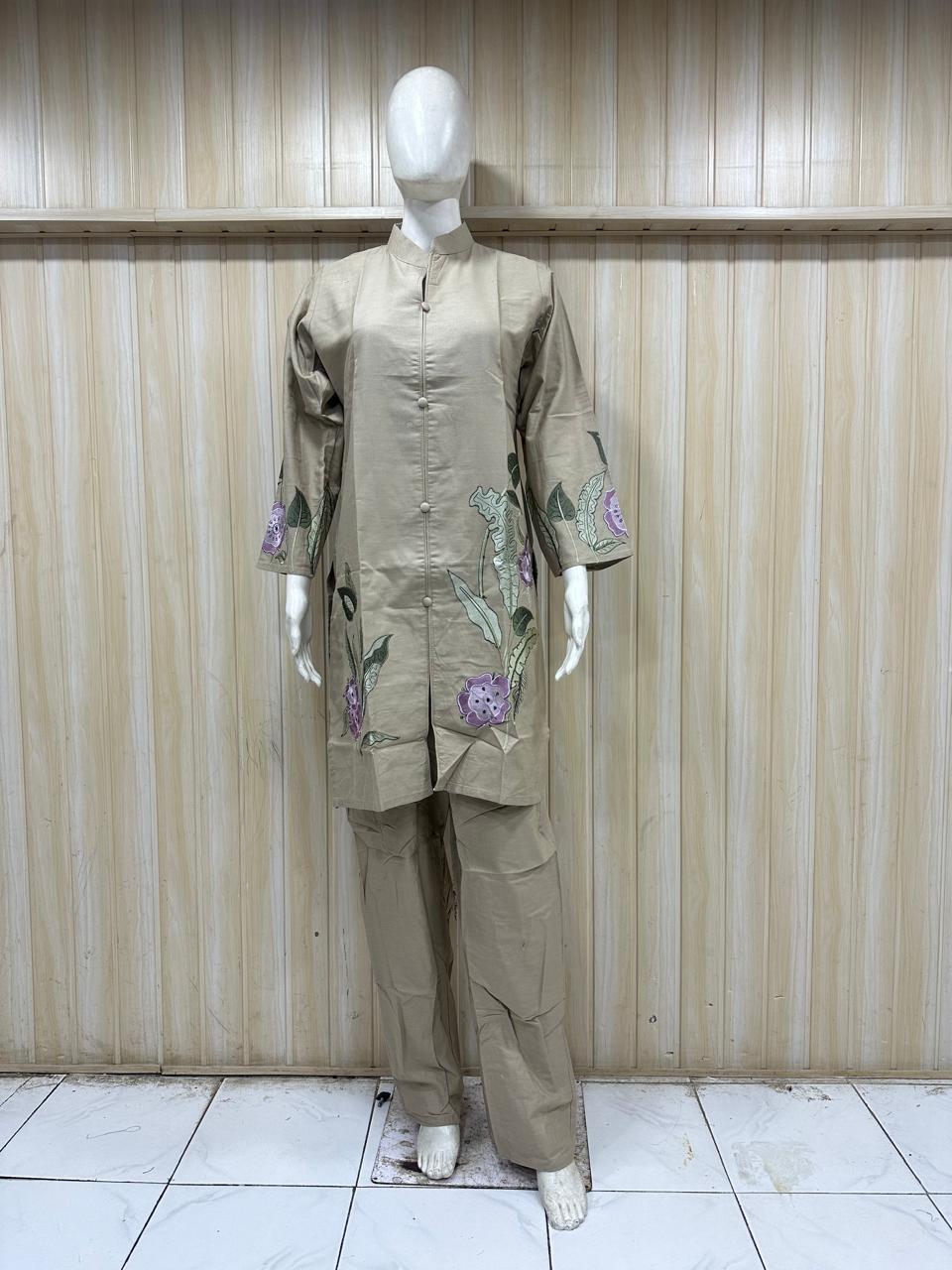 Mannequin wearing a beige embroidered outfit against a striped