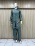 Green embroidered outfit on a mannequin against a striped