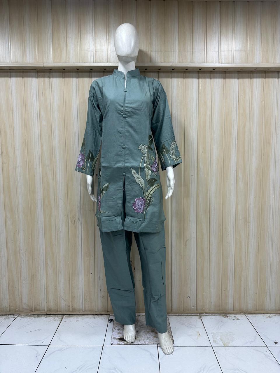 Green embroidered outfit on a mannequin against a striped