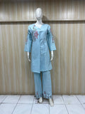 Light blue embroidered outfit on a mannequin against a striped