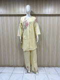 Mannequin wearing a light yellow outfit with floral patterns against a striped
