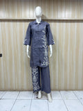 Mannequin wearing a gray outfit with floral patterns against a wooden panel background