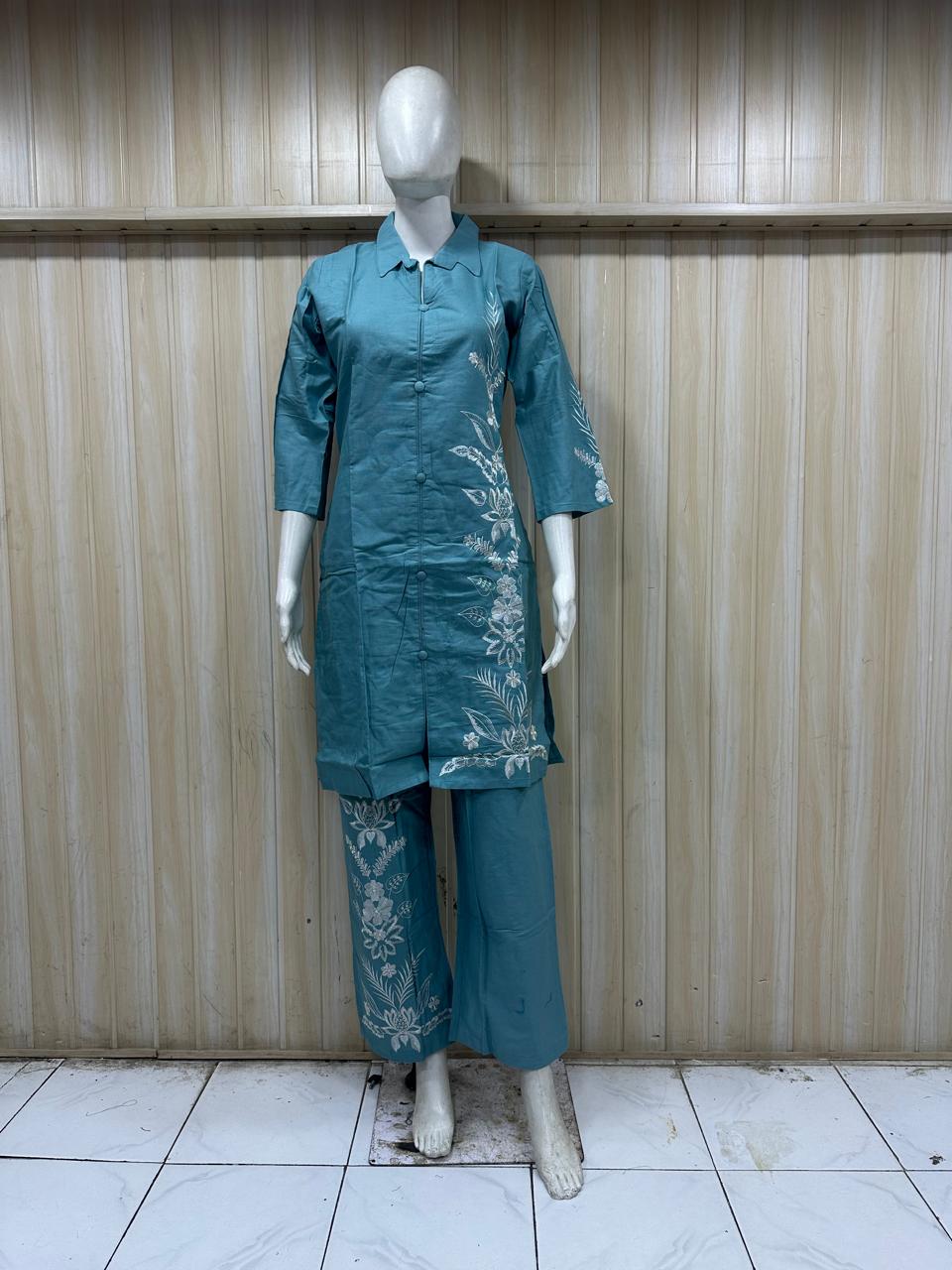 Teal outfit with floral embroidery on a mannequin against a striped