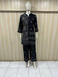 Mannequin wearing a black embroidered outfit against a wooden panel background