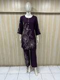 Mannequin wearing a purple outfit with floral embroidery against a wooden panel background