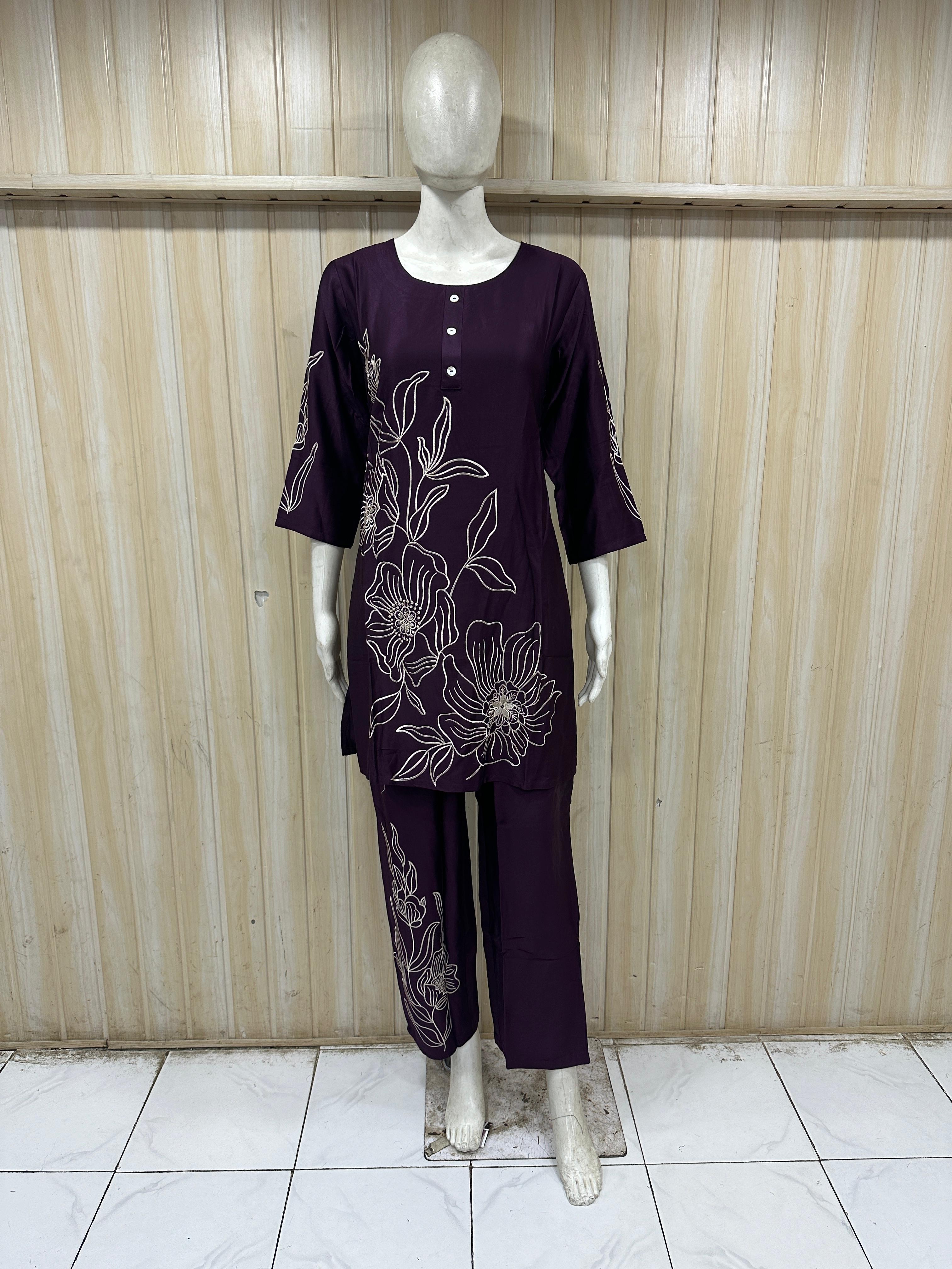Mannequin wearing a purple outfit with floral embroidery against a wooden panel background