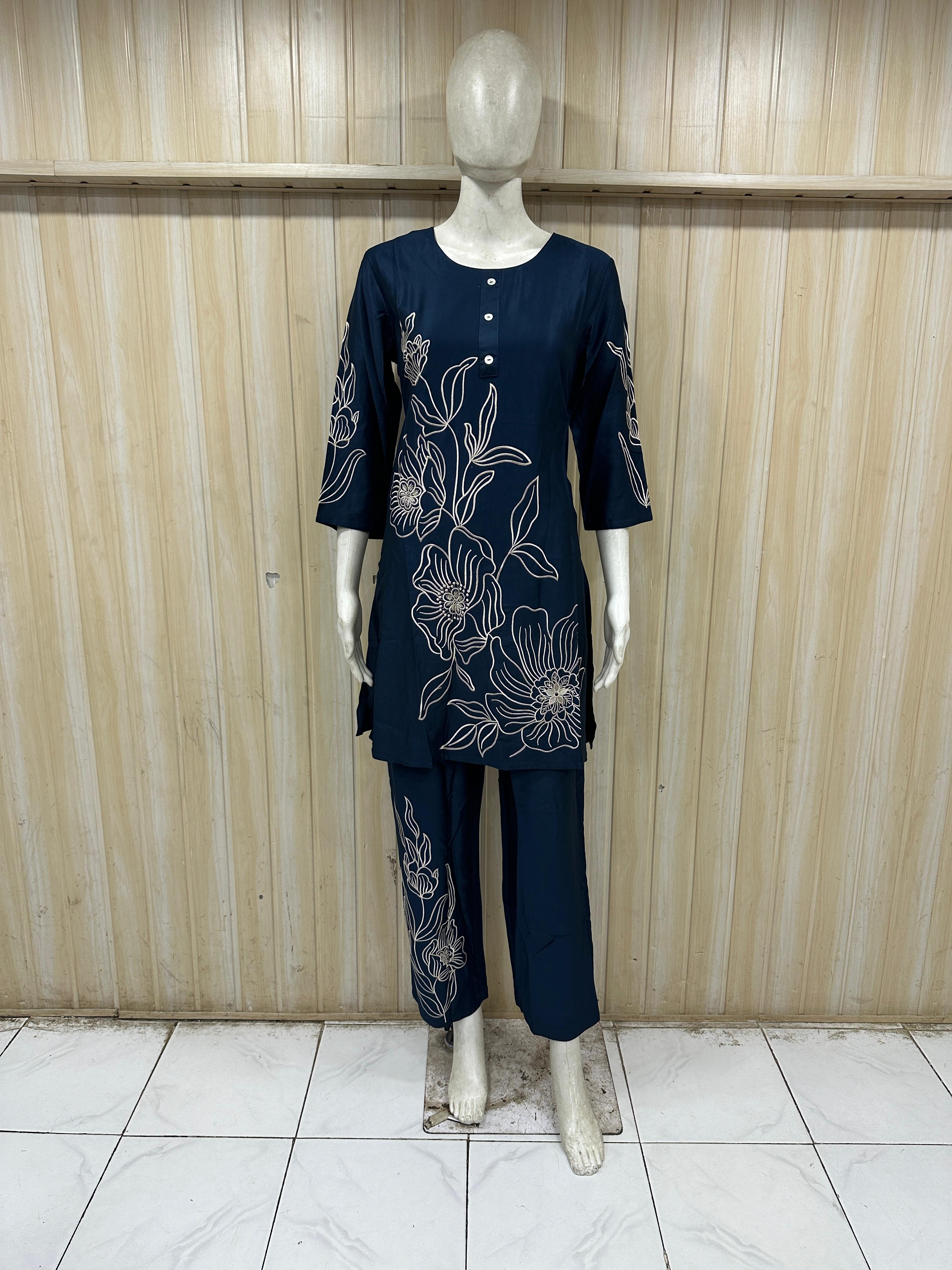 Navy blue outfit with floral embroidery on a mannequin against a wooden panel background