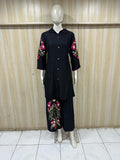 black outfit with floral embroidery on a mannequin against a wooden panel background