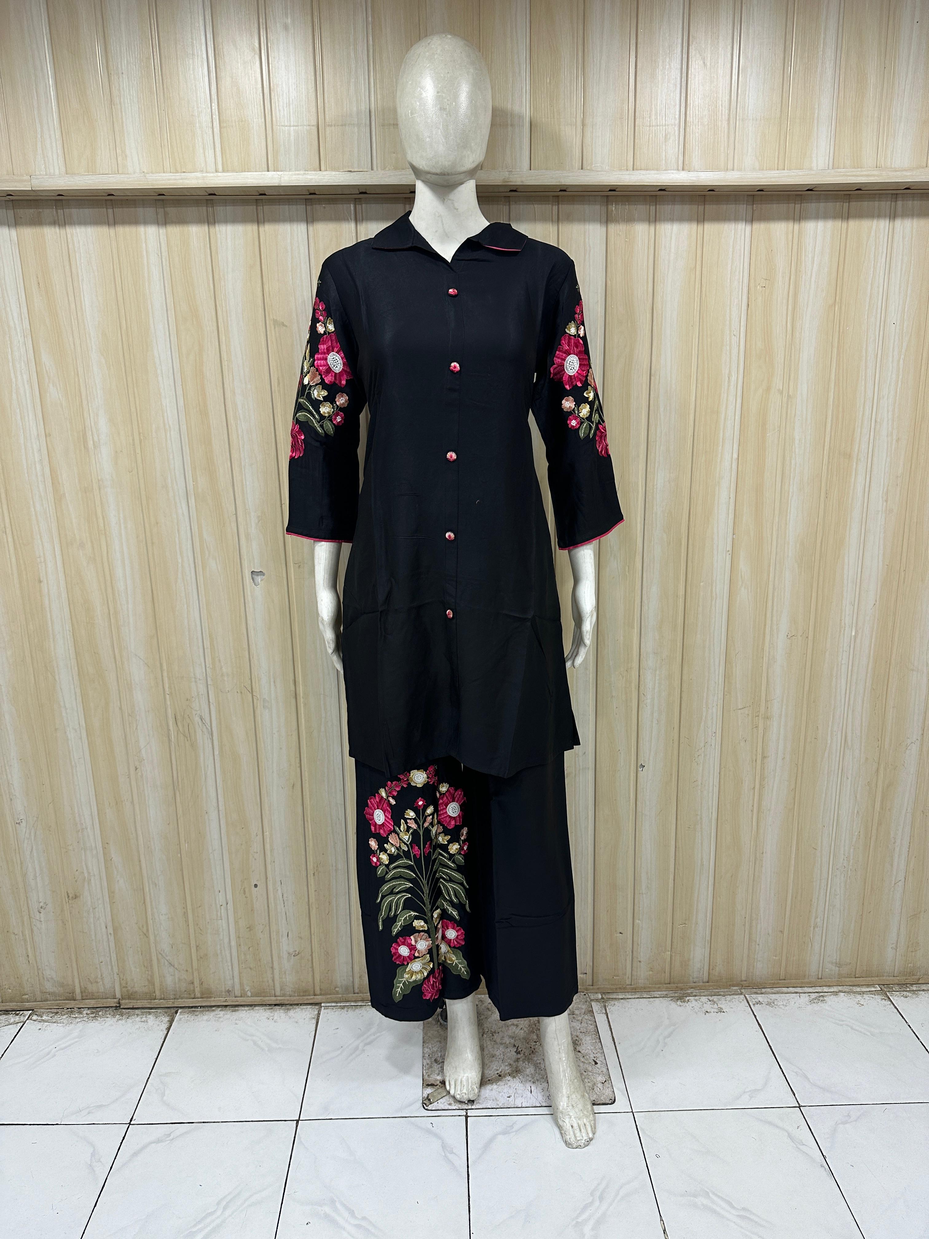 black outfit with floral embroidery on a mannequin against a wooden panel background