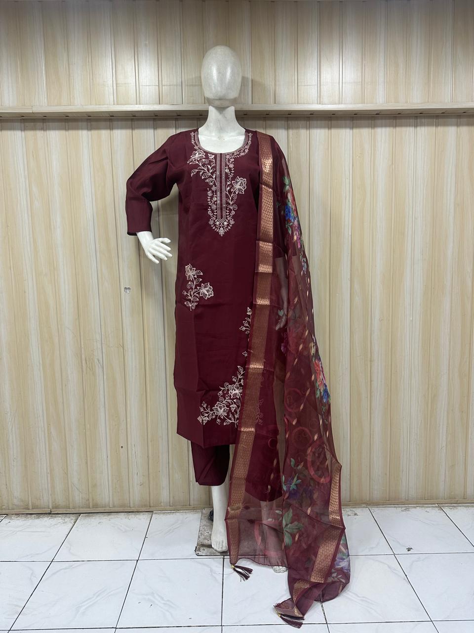 Maroon embroidered outfit with a sheer dupatta on a mannequin against a striped
