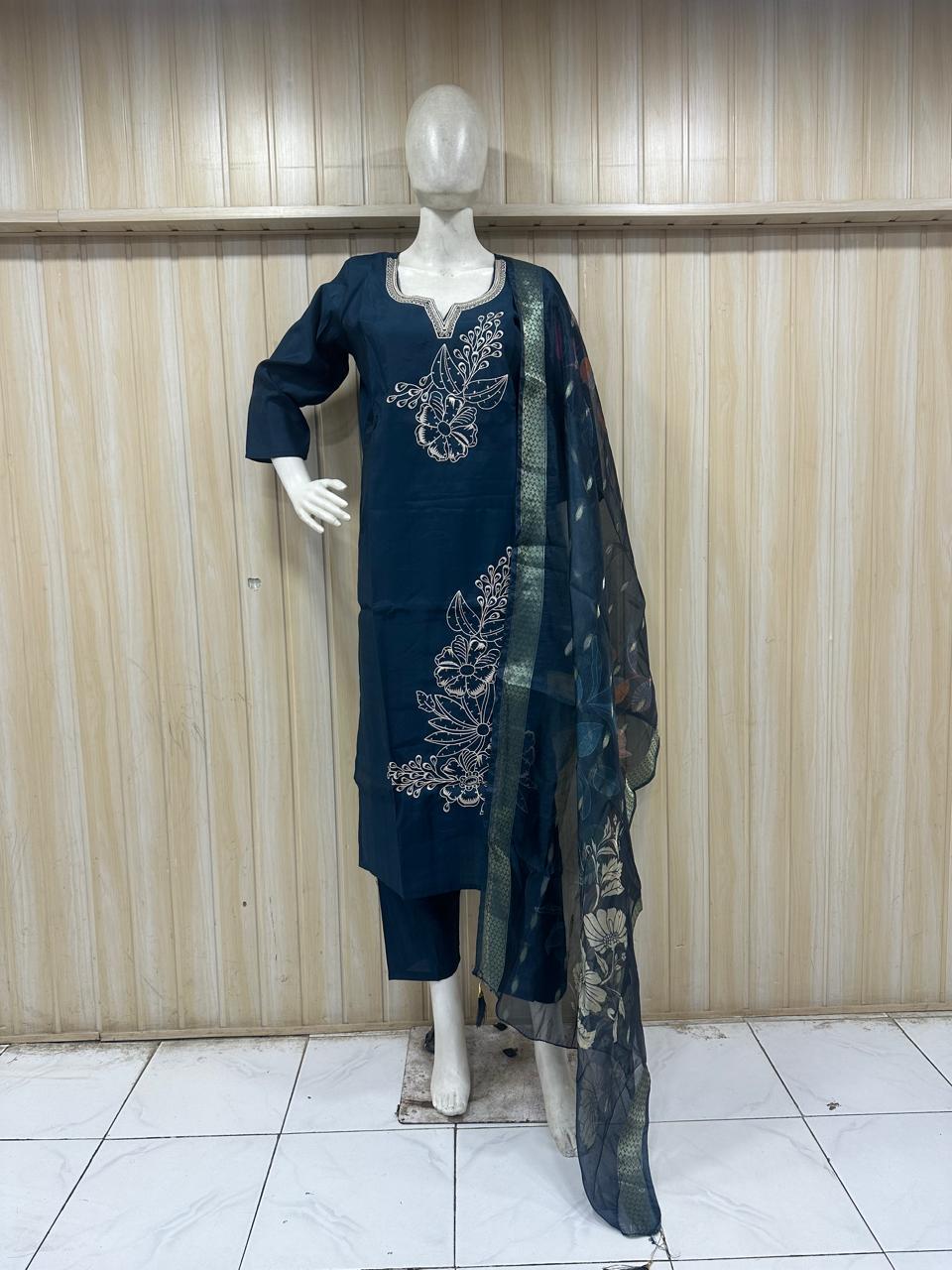Navy blue embroidered outfit with a floral scarf on a mannequin against a striped