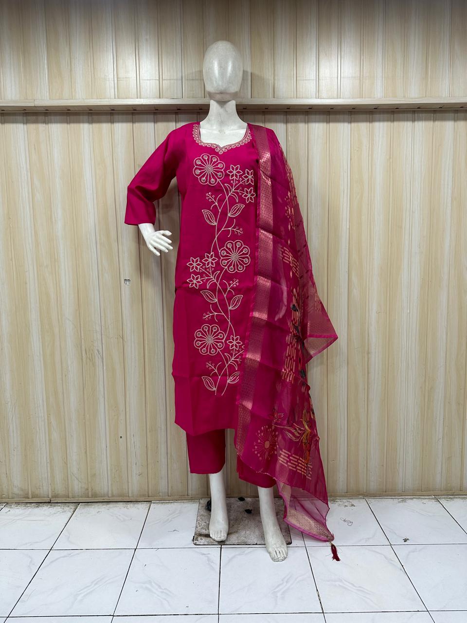 Mannequin wearing a red embroidered outfit with a matching dupatta against a striped