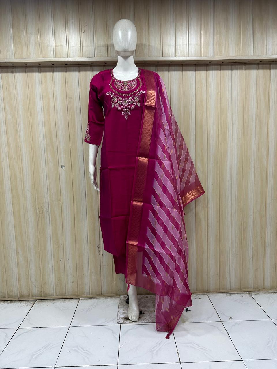 dark pink traditional outfit with embroidery on a mannequin against a striped