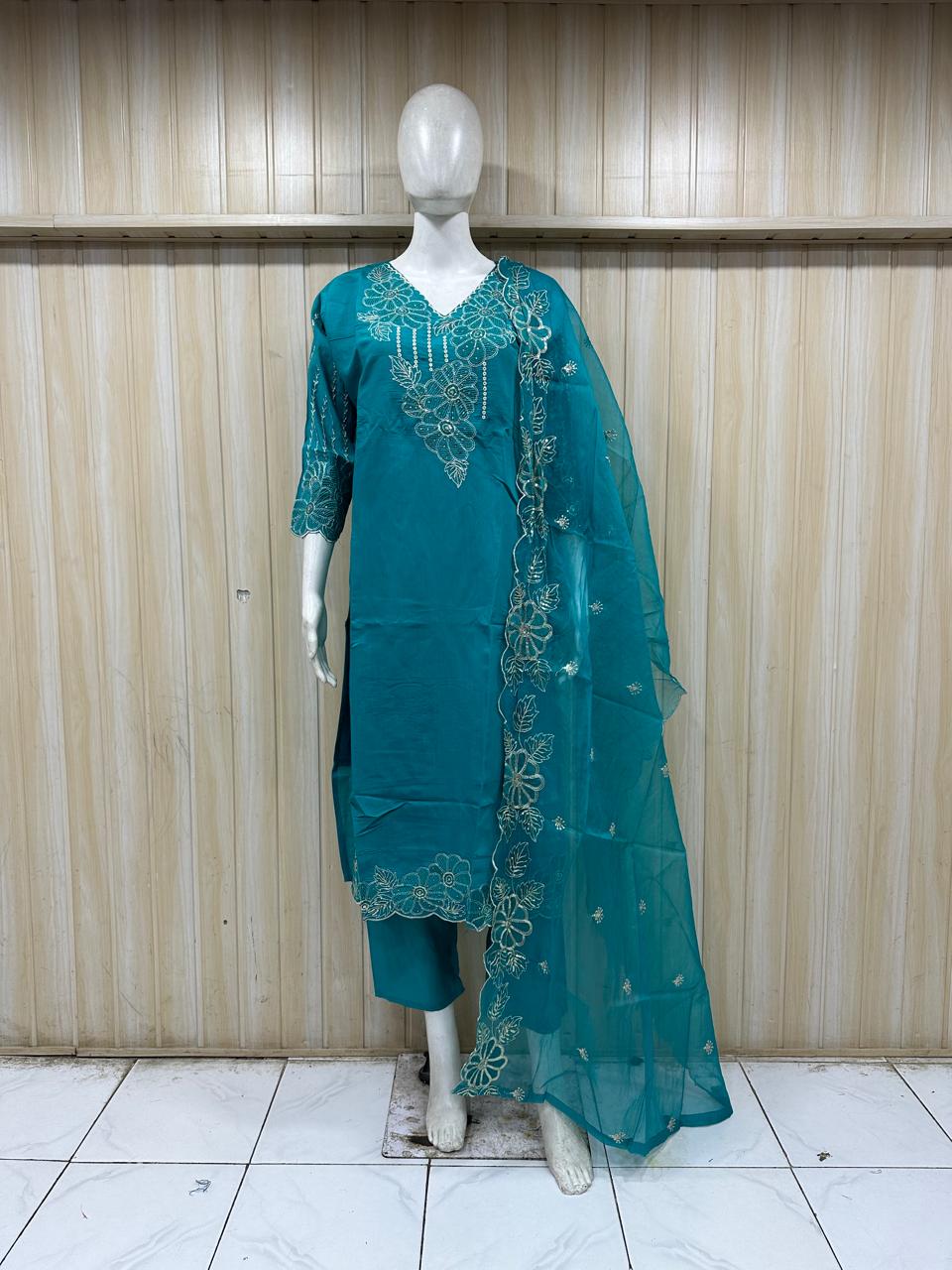 Teal embroidered outfit on a mannequin against a striped