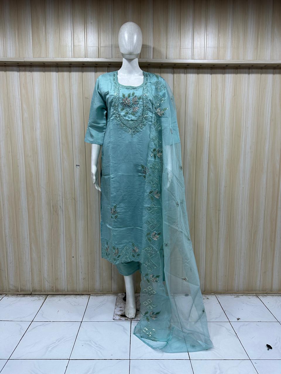 Teal embroidered outfit with a dupatta on a mannequin against a striped