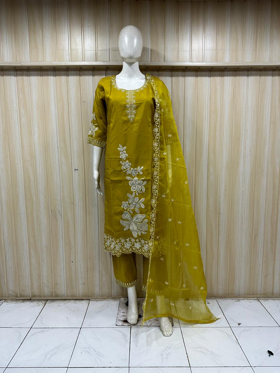 Mannequin wearing a yellow traditional outfit with floral patterns against a striped
