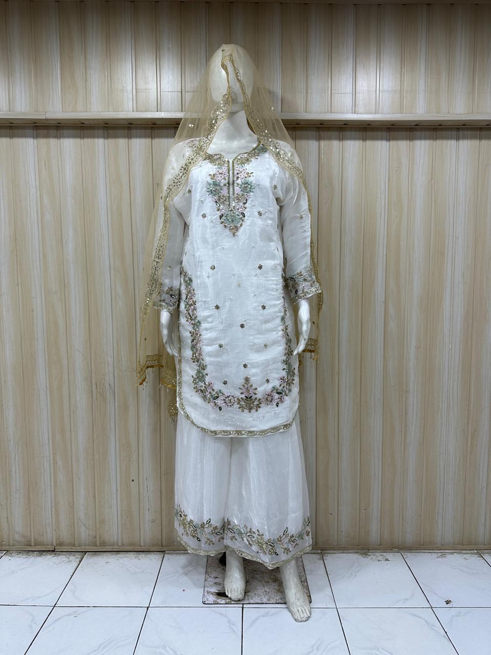 White embroidered traditional outfit on a mannequin against a striped