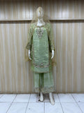 Green embroidered traditional outfit on a mannequin against a striped