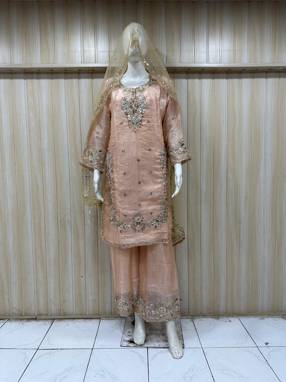 Traditional outfit with embroidered pink dress and dupatta on a mannequin against a striped