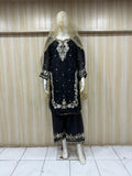 Black embroidered outfit with a veil on a mannequin against a striped
