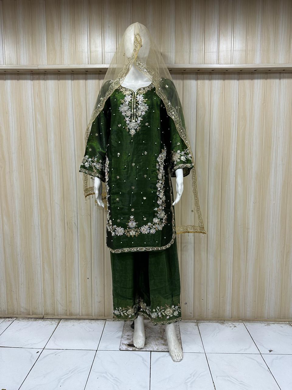 Green embroidered traditional outfit on a mannequin against a striped