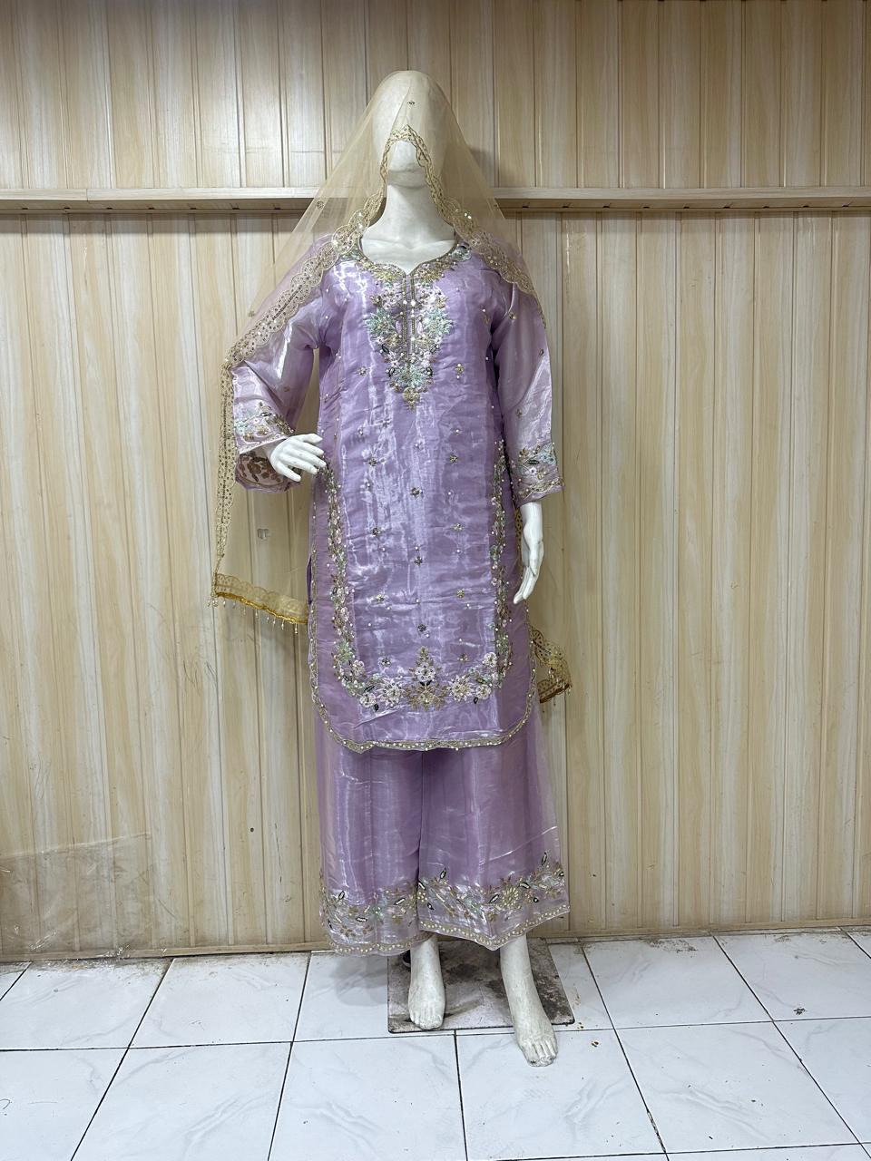 Mannequin wearing a lavender embroidered outfit against a striped