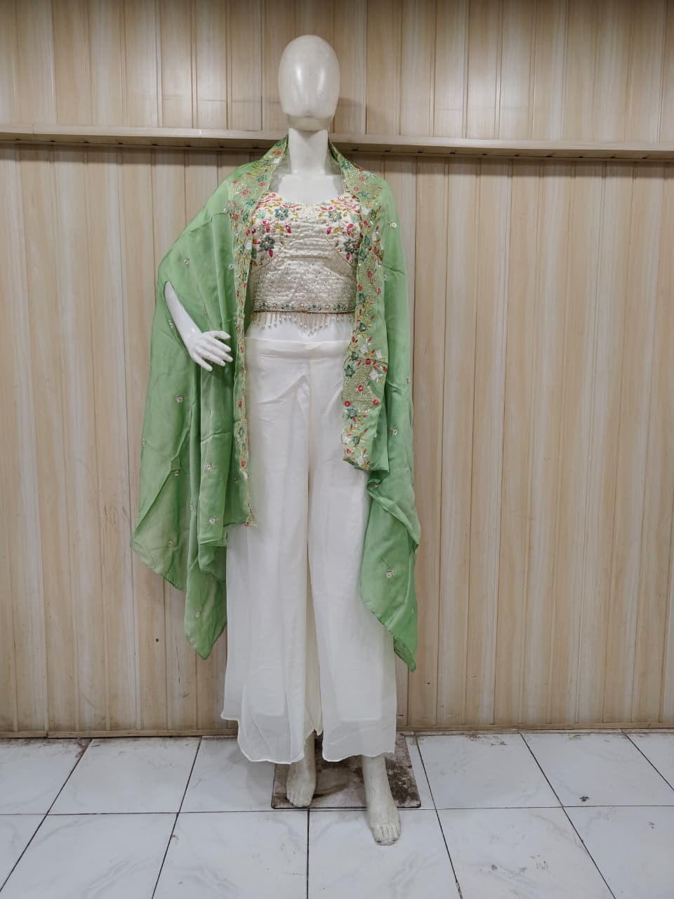 white and green embroidered outfit on a mannequin against a striped