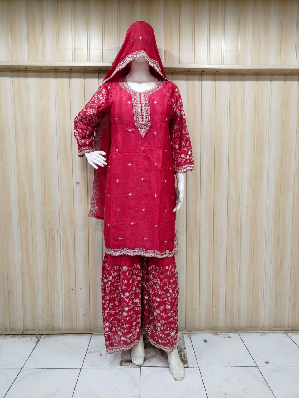 “Elegant pink embroidered outfit on mannequin against striped background – perfect for a soft, graceful & classy ethnic look